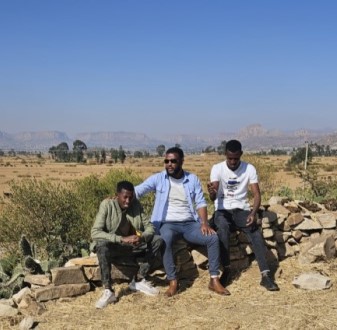 Dr Hailay Gesesew and two men standing in front of Ethiopia landscape