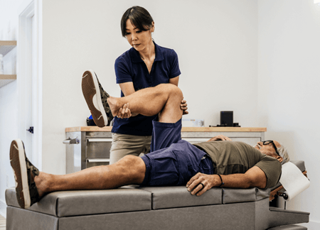 Myotherapist stretching patient knee | Think Education