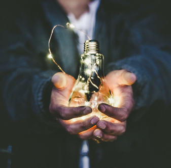 Lightbulb in clasped hands | Social Exchange | Torrens University