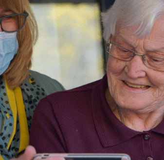 Health professional shows phone to elderly woman