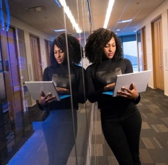 Woman uses laptop standing next to IT systems