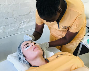 student applying eyelashes to a client